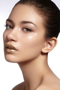 Young Beautiful Woman with clean soft Skin, bright gold Lips Makeup. Perfect eyebrows shapes. Day look make-up with gloss