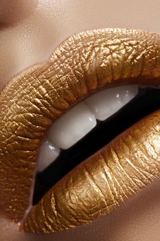 Beautiful closeup with female plump lips with gold color makeup. Fashion celebrate make-up, glitter cosmetic. Shine christmas style. Metalic makeup