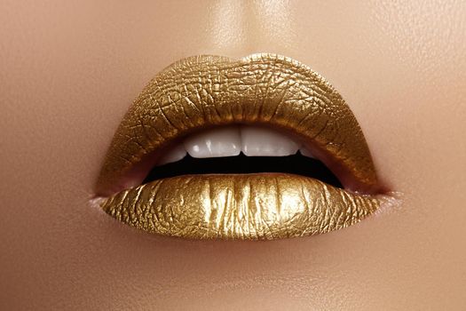 Beautiful closeup with female plump lips with gold color makeup. Fashion celebrate make-up, glitter cosmetic. Shine christmas style. Metalic makeup