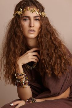 Beautiful Woman. Curly Long Hair. Fashion Model with Healthy Wavy Hairstyle. Accessories. Boho Girl with Autumn Wreath, Gold Floral Crown. Vertical shot