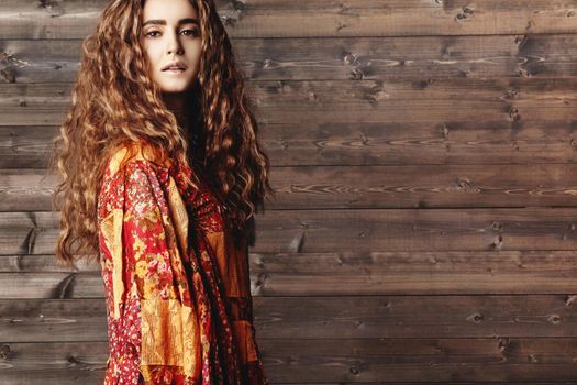 Beautiful young woman with long curly hairstyle, fashion jewelry with long brunette hair. Sexy girl in vogue style. Pretty arabian beauty portrait of female face. Indian style clothes, long dress