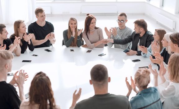 young people greet each other at a round table meeting . photo with copy space