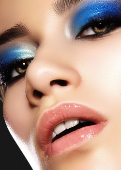 Glamour portrait of beautiful woman model with bright evening makeup with blue color and clean healthy skin face. Blue wet make up