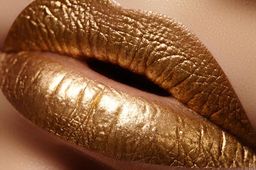 Beautiful closeup with female plump lips with gold color makeup. Fashion celebrate make-up, glitter cosmetic. Shine christmas style. Metalic makeup