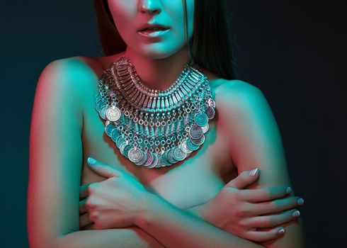 Beautiful woman in a necklace. Model in jewelry from silver. Beautiful indian jewellery. Bright lights photo effect