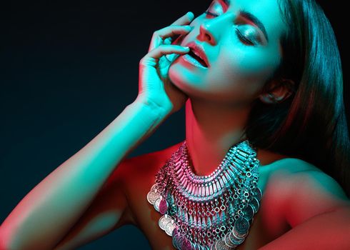 Beautiful woman in a necklace. Model in jewelry from silver. Beautiful indian jewellery. Bright lights photo effect