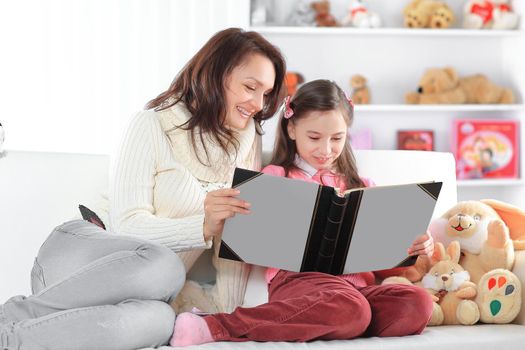 charming mother and daughter reading a book sitting on the couch.photo with copy space.