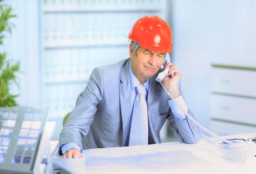 Engineer at the age of talking on the phone about the plans of the drawing.