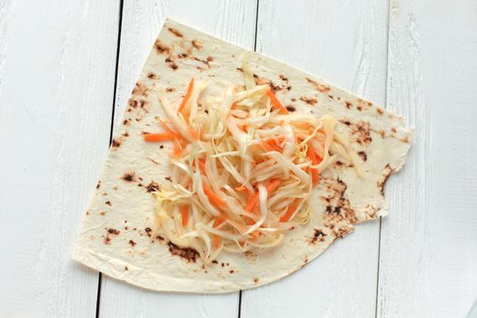 cabbage salad and pita bread on the wooden table.