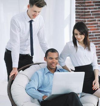 successful businessman with his assistants in a discussion of the information from the laptop.office life