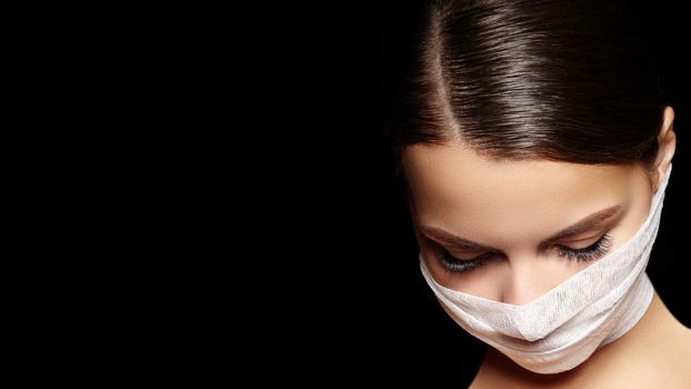 Beautiful woman with a bandage mask on face. Fashion eye make-up. Beauty plastic surgery or protection hygiene in viral covid-19 pandemic