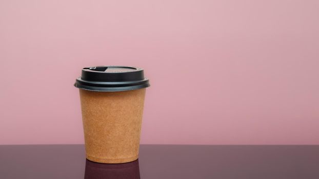 coffee to go in a disposable cup on the table and pink background. space for text. photo