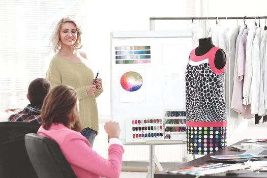 woman pointing at swatch color palette while discussing what color to choose with colleague.