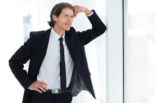 smiling businessman standing near window in office.the concept of perspective.