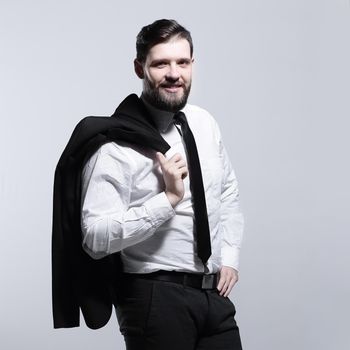 smiling businessman holding a jacket over his shoulder and straightens the tie.