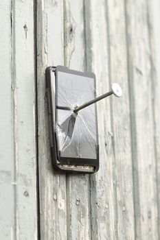 faulty mobile phone is nailed to an old fence.the concept of obsolete technology