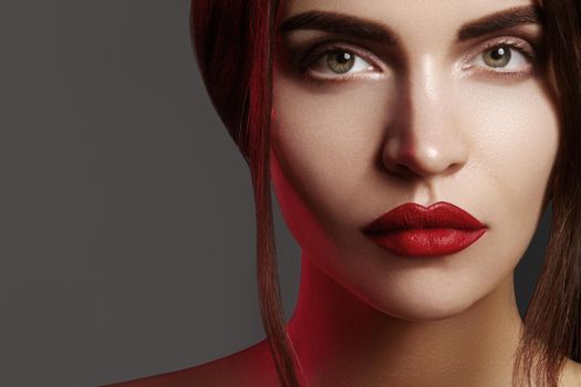 Closeup portrait with of beautiful woman face. Red color of fashion lip makeup, clean shiny skin and strong eyebrows. Makeup and cosmetic. Beauty style