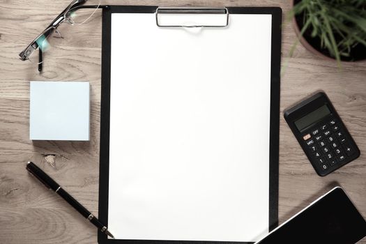 clipboard with blank sheet smartphone and calculator on wooden background.