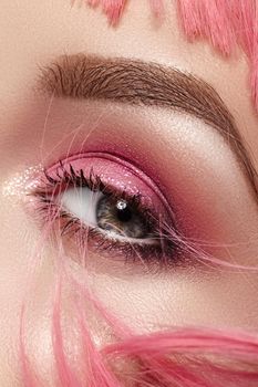 Closeup Macro of Pink Fashion Eye Make-up. Expressive Makeup, Bright Summer Eyeshadows and Magenta Color Hair, Shiny Skin