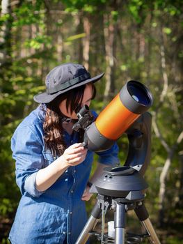 Portrait of young woman looking through the telescope on the hil. photo