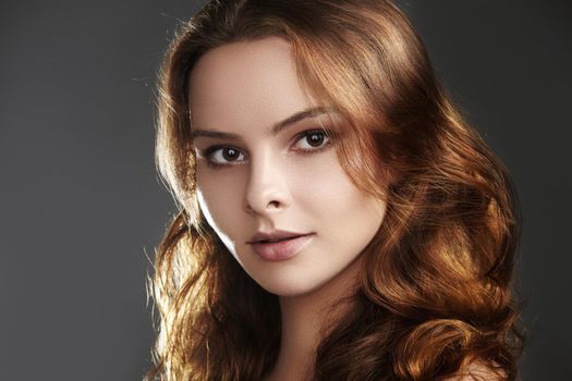 Beautiful young woman model with flying brown color hair. Beauty portrait with clean skin, glow glamour fashion makeup. Make up, curly hairstyle. Hair-care, make-up. Horizontal beauty portrait