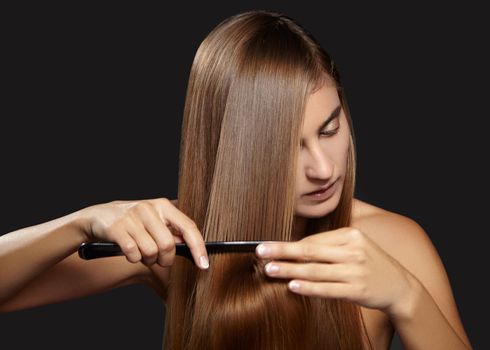 Hair care photo. Beautiful woman after Bath Hairbrushing Healthy Straight Brown Hair. Model Brushing Her Long Hair on black background
