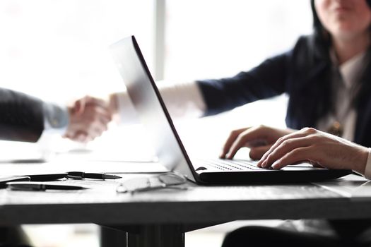 close up.businessman working on laptop on the background of handshake of business partners