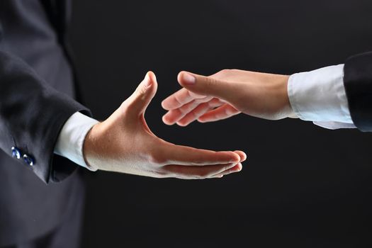 Photo of hands of business partners before handshake in black background