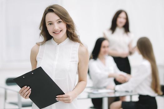 successful young business woman with clipboard in the background of the office.