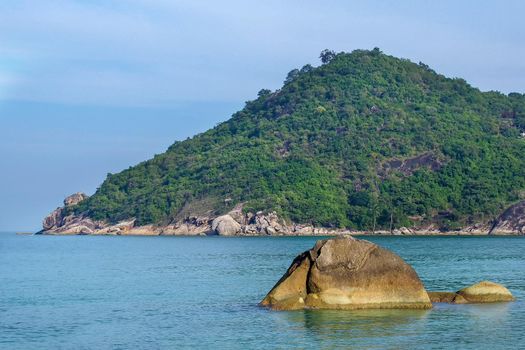 Rocky rock over beautiful clear sea and island, view from Kho Phangan, Thailand.