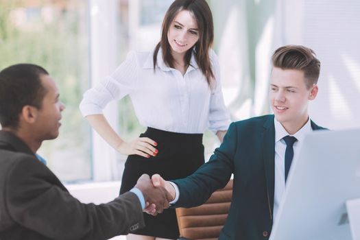 handshake of business partners sitting at a Desk .the concept of partnership