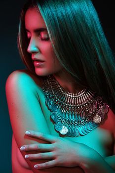 Beautiful woman in a necklace. Model in jewelry from silver. Beautiful indian jewellery. Bright lights photo effect