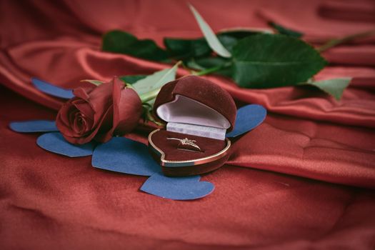 diamond ring and rose on bright red background. photo with copy space