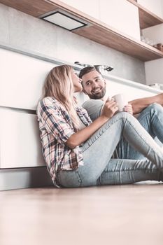 close up. young couple drinking coffee sitting on the kitchen floor