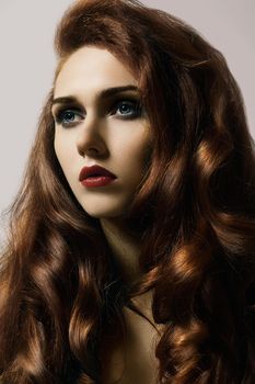 Beautiful ginger young woman with luxury hair style and fashion gloss makeup. Beauty portrait of sexy model with red hair. Long soft shiny hairstyle. Close-up studio shot of look redhead girl