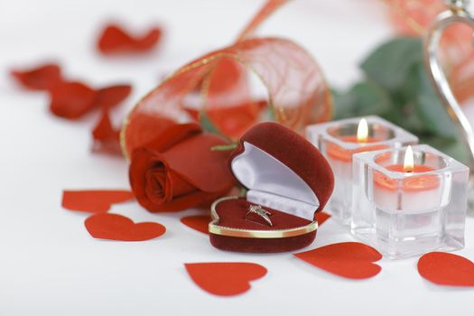 wedding rings, candles and rose on white background.