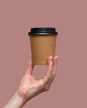 Woman hands hold paper cup on pink background. Copy space. photo