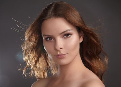 Beautiful young woman model with flying brown color hair. Beauty portrait with clean skin, glow glamour fashion makeup. Make up, curly hairstyle. Hair-care, make-up. Horizontal beauty portrait