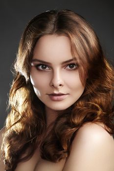 Beautiful young woman model with flying brown color hair. Beauty portrait with clean skin, glow glamour fashion makeup. Make up, curly hairstyle. Hair-care, make-up. Horizontal beauty portrait