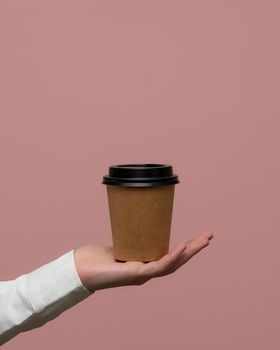 Woman hands hold paper cup on pink background. Copy space. photo