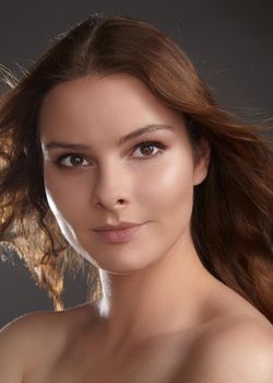 Beautiful young woman model with flying brown color hair. Beauty portrait with clean skin, glow glamour fashion makeup. Make up, curly hairstyle. Hair-care, make-up. Horizontal beauty portrait