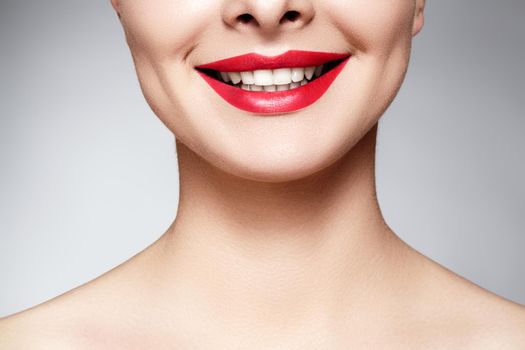 Wide smile of young beautiful woman with perfect healthy white teeth on grey background. Dental whitening, ortodont, care tooth and wellness. Red lipstick makeup on female lips.