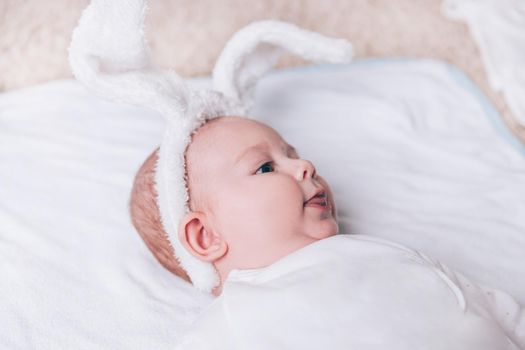 close up.pretty baby in a rabbit suit lying on the bed. holiday concept