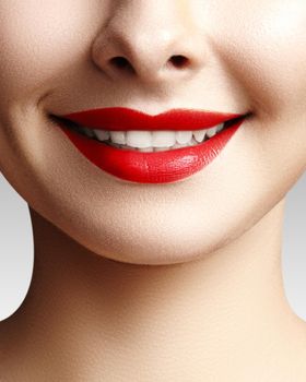 Wide smile of young beautiful woman with perfect healthy white teeth on grey background. Dental whitening, ortodont, care tooth and wellness. Red lipstick makeup on female lips.