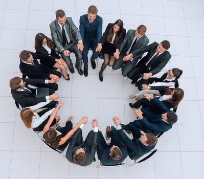 concept of team building.large business team sitting in a circle and holding each other's hands