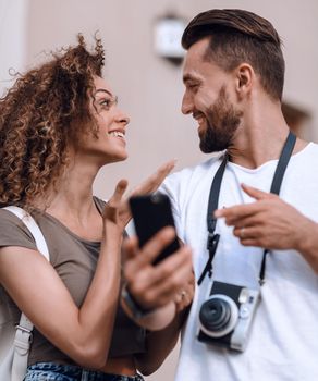 Happy young couple searching for location both on mobile phone