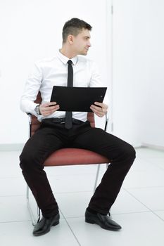 attentive businessman with clipboard sitting on office chair.