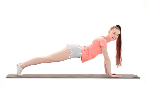 Young woman exercising - doing a plank in a studio.