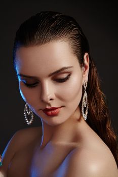 Beautiful woman in luxury fashion earrings. Diamond shiny jewelry with brilliants. Sexy retro style portrait. Model with glamour accessories jewelery, fashion makeup, clean shiny skin and wet hair