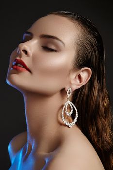 Beautiful woman in luxury fashion earrings. Diamond shiny jewelry with brilliants. Sexy retro style portrait. Model with glamour accessories jewelery, fashion makeup, clean shiny skin and wet hair